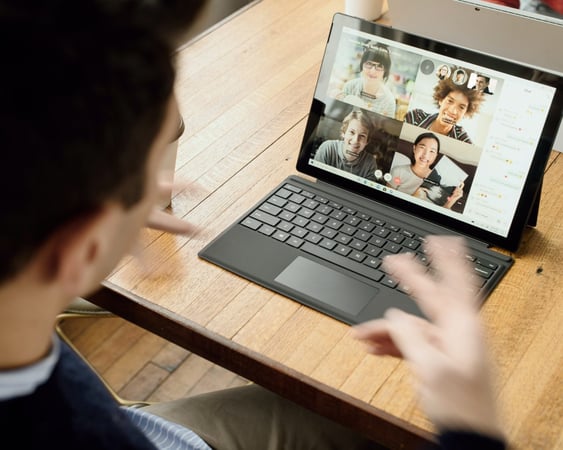 A man talking to his colleagues via video call as he works remotely.